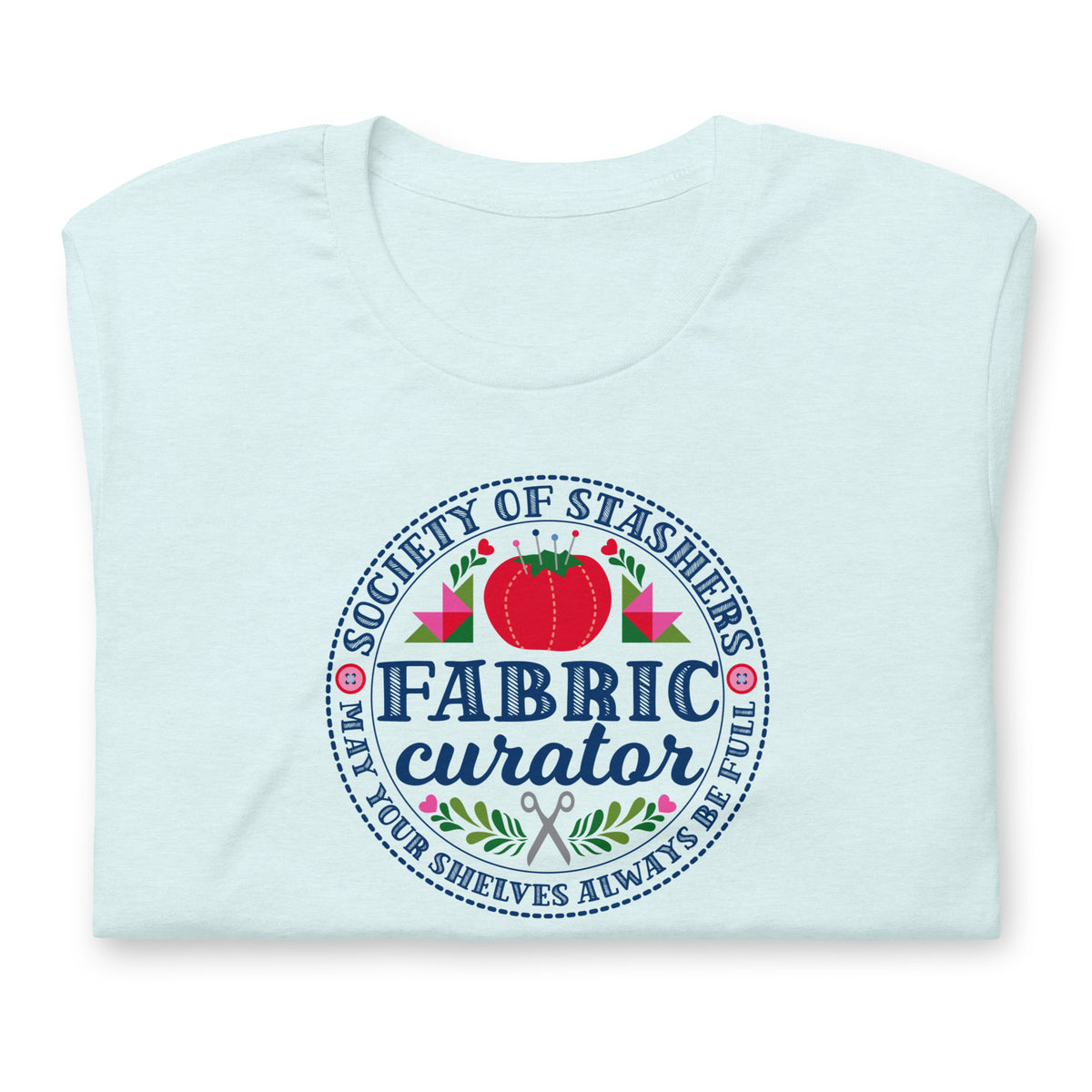 Fabric Curator Society of Stashers badge with a tomato pincushion on a t-shirt in heather ice blue, folded close-up of the design – Kate Spain design for Pat Sloan