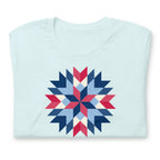 Barn Star quilt block in red, white and blue on a t-shirt in heather ice blue, folded close-up of the design – Kate Spain design for Pat Sloan