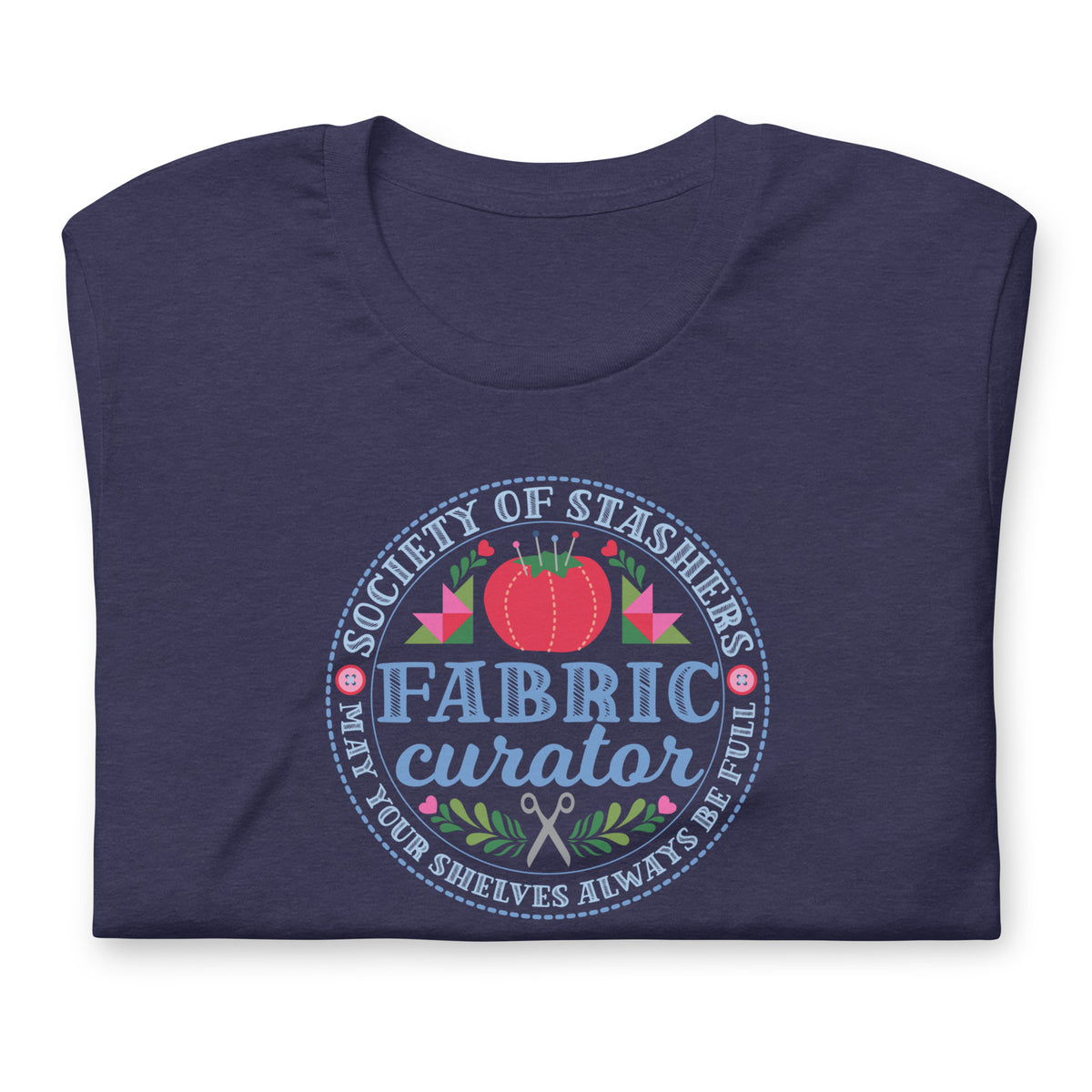 Fabric Curator Society of Stashers badge with a tomato pincushion on a t-shirt in heather navy, folded close-up of the design – Kate Spain design for Pat Sloan
