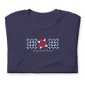 Firecracker quilt-block stars with script lettering in red, white and blue on a t-shirt in heather navy, folded close-up of the design – Kate Spain design for Pat Sloan