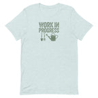 Garden Work in Progress distressed lettering with a shovel, pitchfork and watering can on a t-shirt in heather prism ice blue, front view – Kate Spain design
