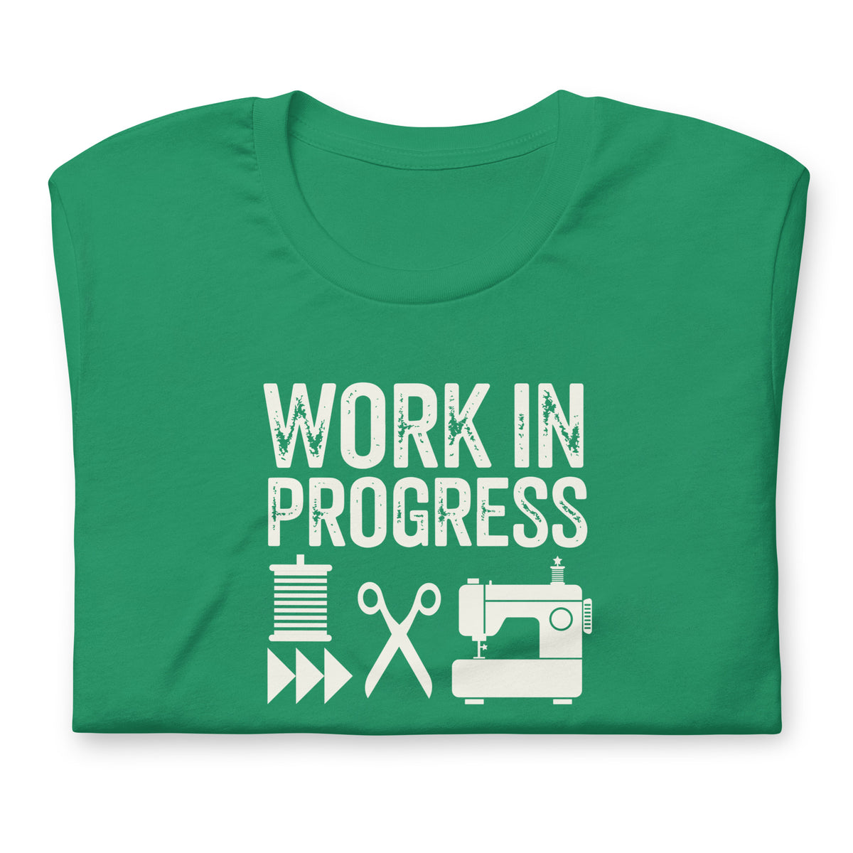 Work in Progress Mod distressed lettering with thread, scissors and sewing machine on a t-shirt in kelly green, folded close-up of the design – Kate Spain design for Pat Sloan