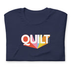Moda QUILT logo with orange, pink, blue and yellow rays on a staple t-shirt in navy, folded close-up of the design – Kate Spain design