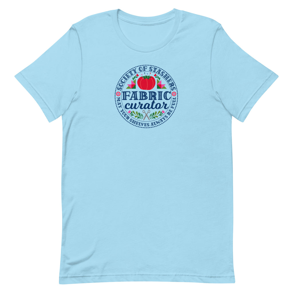 Fabric Curator Society of Stashers badge with a tomato pincushion on a t-shirt in ocean blue, front view – Kate Spain design for Pat Sloan