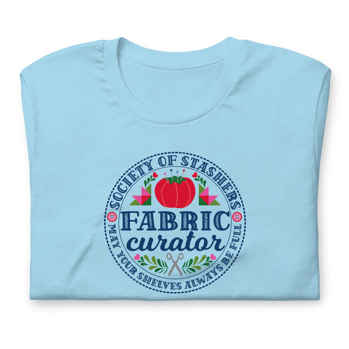 Fabric Curator Society of Stashers badge with a tomato pincushion on a t-shirt in ocean blue, folded close-up of the design – Kate Spain design for Pat Sloan