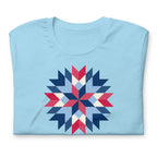Barn Star quilt block in red, white and blue on a t-shirt in ocean blue, folded close-up of the design – Kate Spain design for Pat Sloan