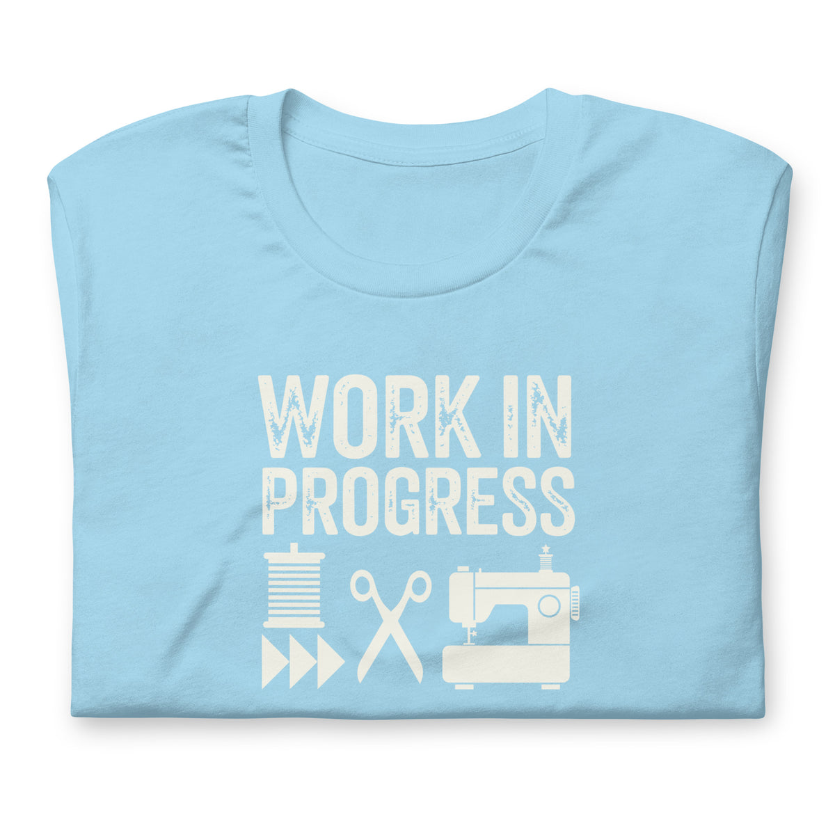 Work in Progress Mod distressed lettering with thread, scissors and sewing machine on a t-shirt in ocean blue, folded close-up of the design – Kate Spain design for Pat Sloan