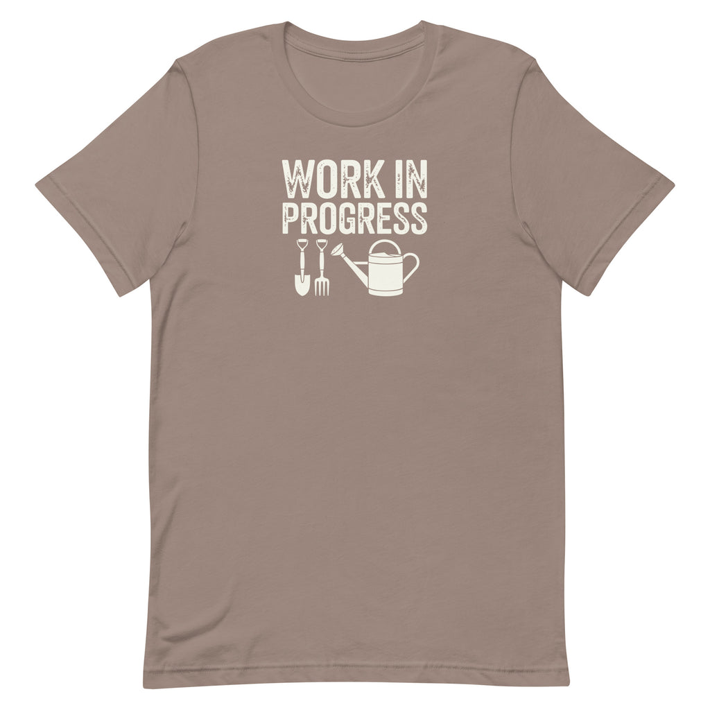 Garden Work in Progress distressed lettering with a shovel, pitchfork and watering can on a t-shirt in pebble, front view – Kate Spain design