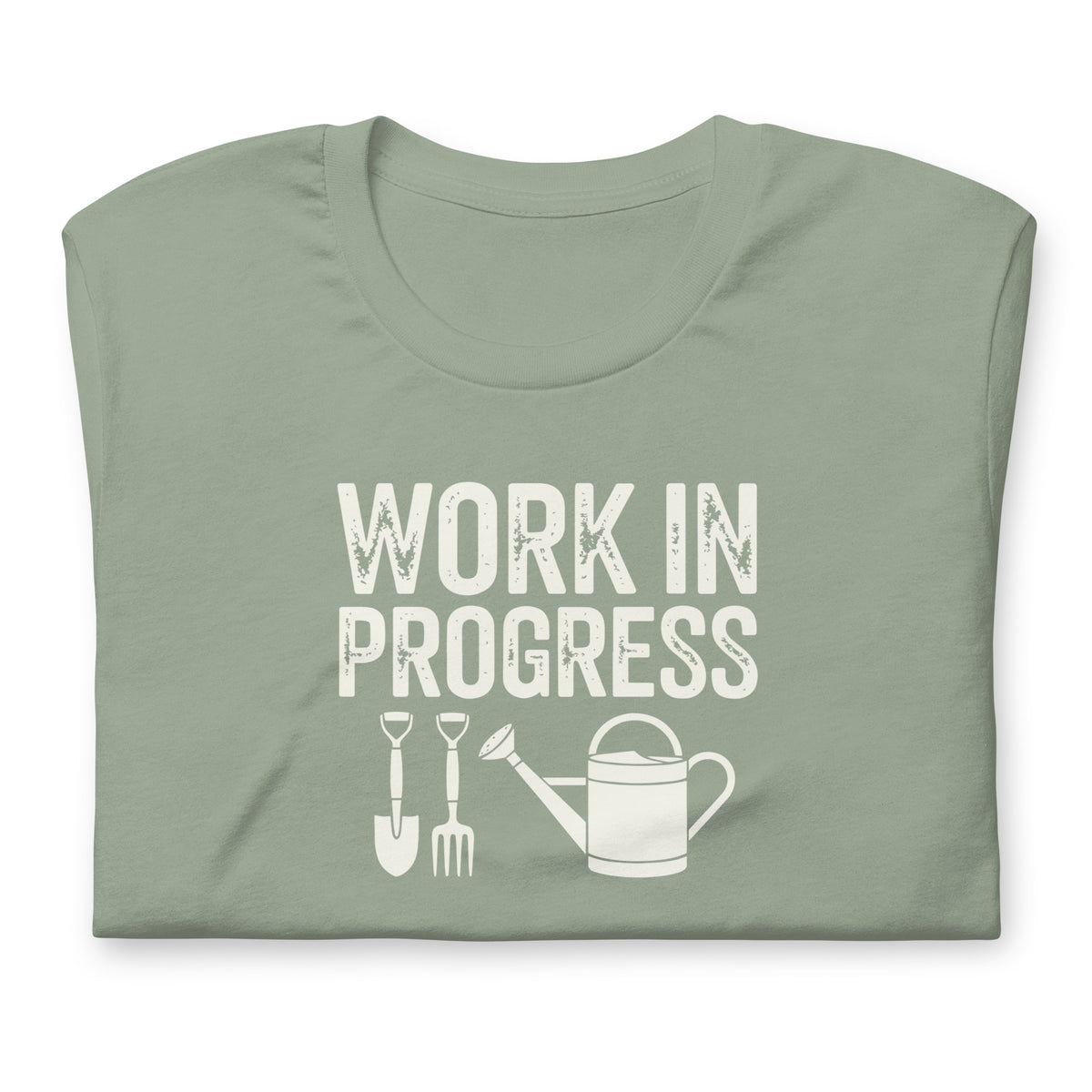 Garden Work in Progress distressed lettering with a shovel, pitchfork and watering can on a t-shirt in sage, folded close-up of the design – Kate Spain design