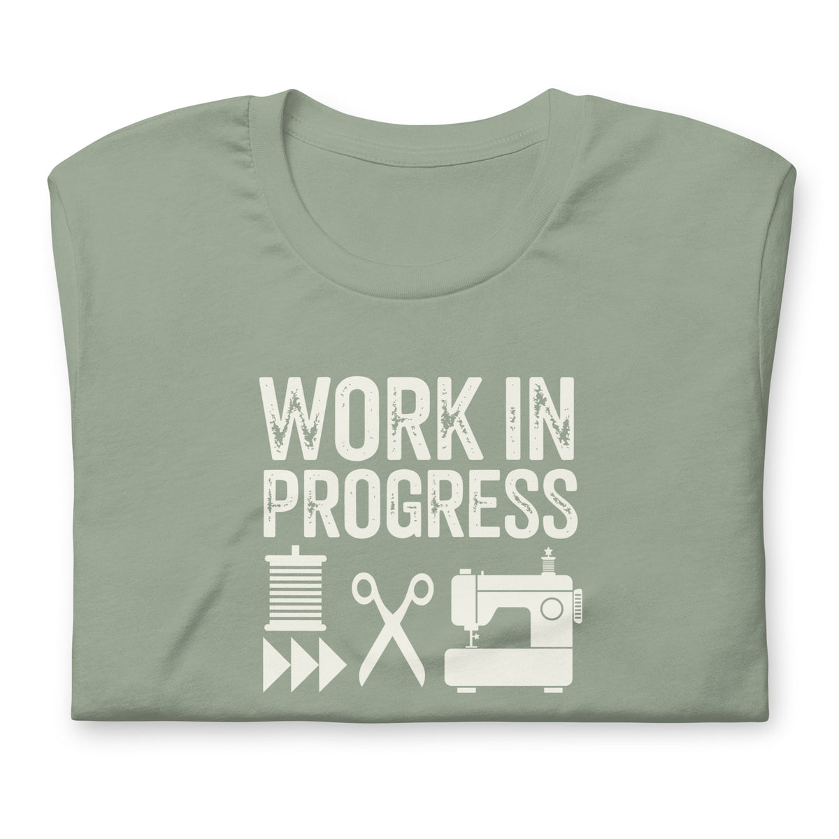 Work in Progress Mod distressed lettering with thread, scissors and sewing machine on a t-shirt in sage, folded close-up of the design – Kate Spain design for Pat Sloan