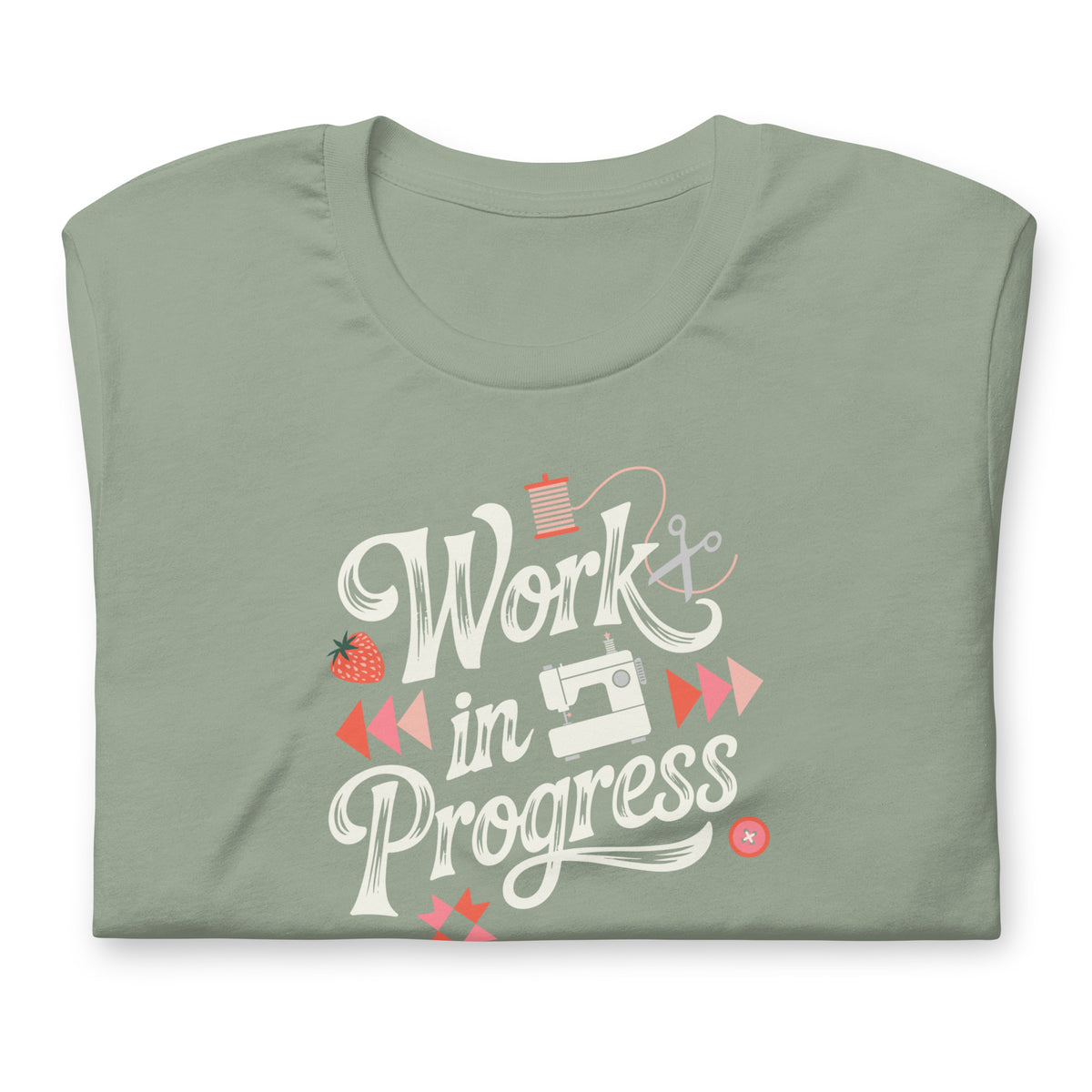 Work in Progress sewing design with flying geese, sewing machine, strawberry and thread spool on a t-shirt in sage, folded close-up of the design – Kate Spain design for Pat Sloan