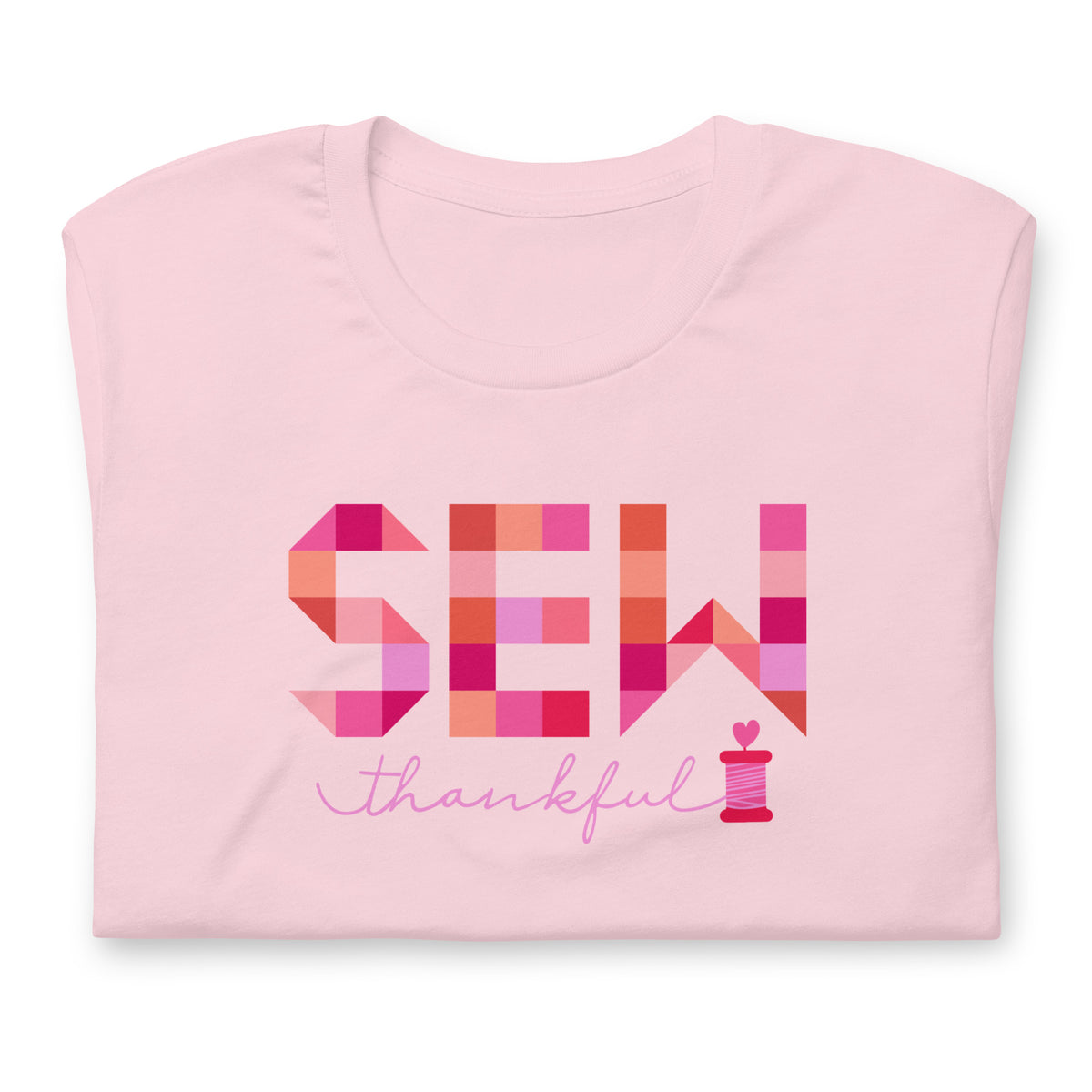 Sew Thankful patchwork lettering with a heart-topped thread spool on a t-shirt in pink, folded close-up of the design – Kate Spain design for Pat Sloan