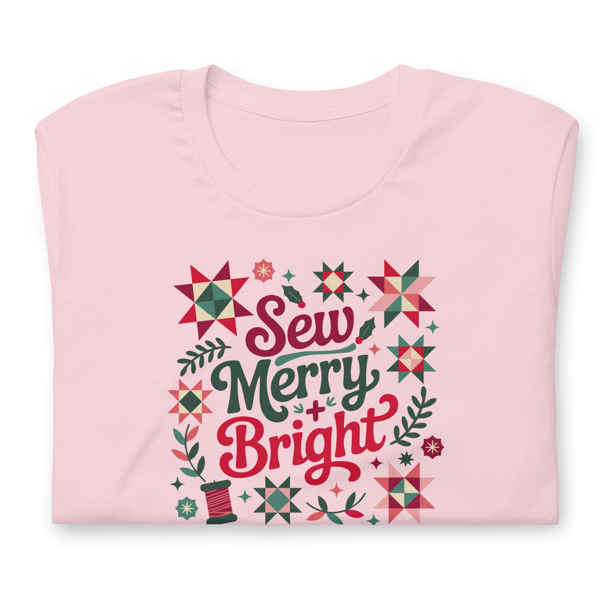 Sew Merry + Bright lettering with quilt stars and holly on a staple t-shirt in soft pink, folded close-up of the design – Kate Spain design for Pat Sloan