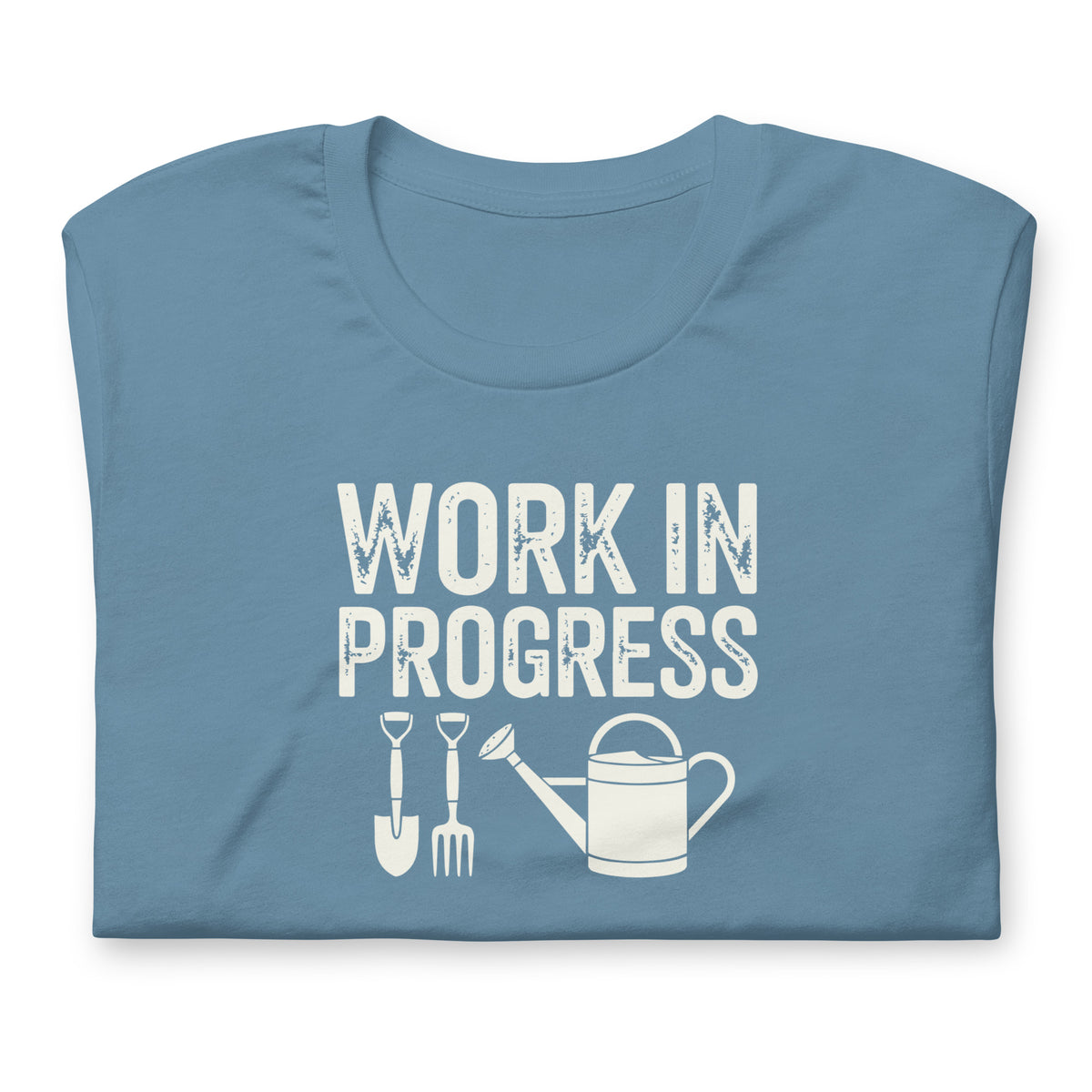 Garden Work in Progress distressed lettering with a shovel, pitchfork and watering can on a t-shirt in steel blue, folded close-up of the design – Kate Spain design
