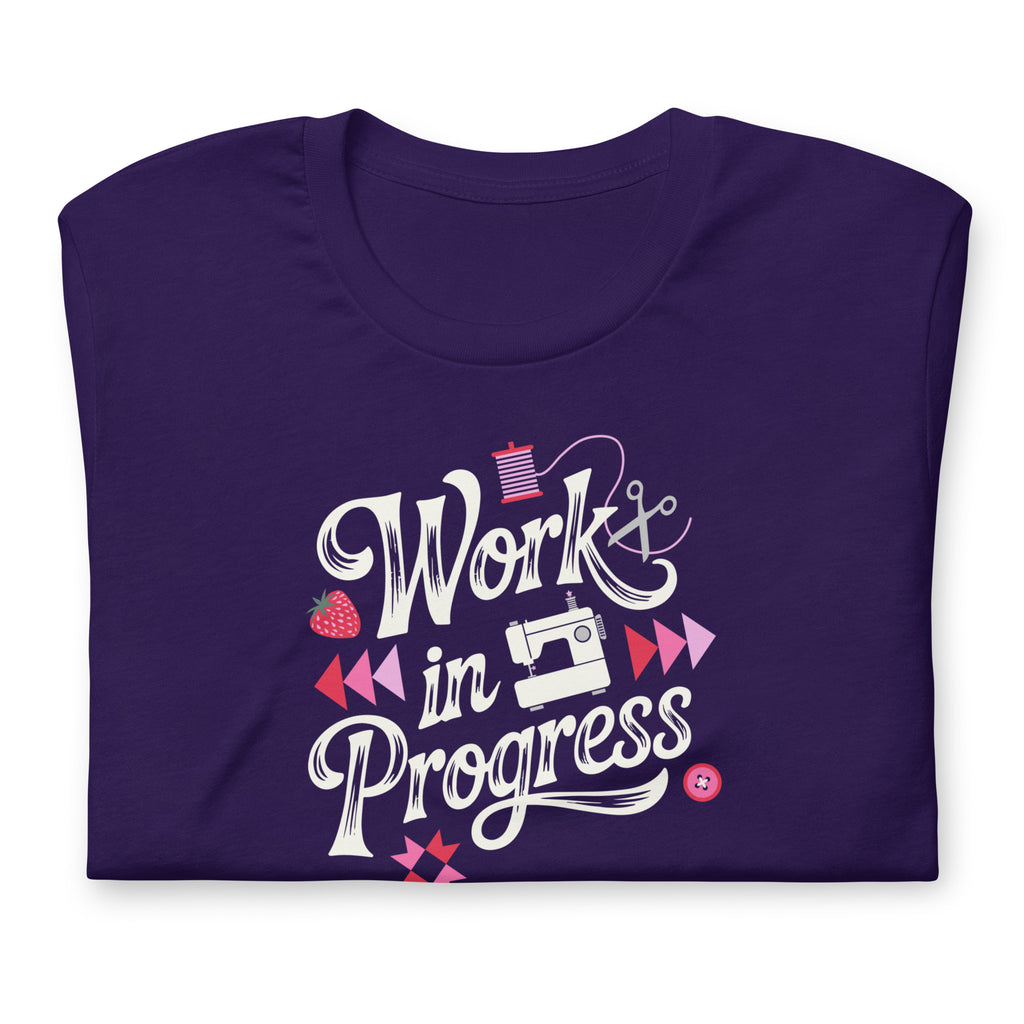 Work in Progress sewing design with flying geese, sewing machine, strawberry and thread spool on a t-shirt in purple, folded close-up of the design – Kate Spain design for Pat Sloan