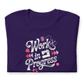 Work in Progress sewing design with flying geese, sewing machine, strawberry and thread spool on a t-shirt in purple, folded close-up of the design – Kate Spain design for Pat Sloan