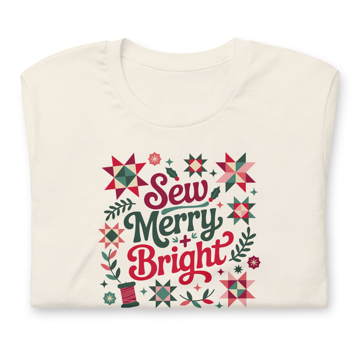 Sew Merry + Bright lettering with quilt stars and holly on a staple t-shirt in vintage white, folded close-up of the design – Kate Spain design for Pat Sloan