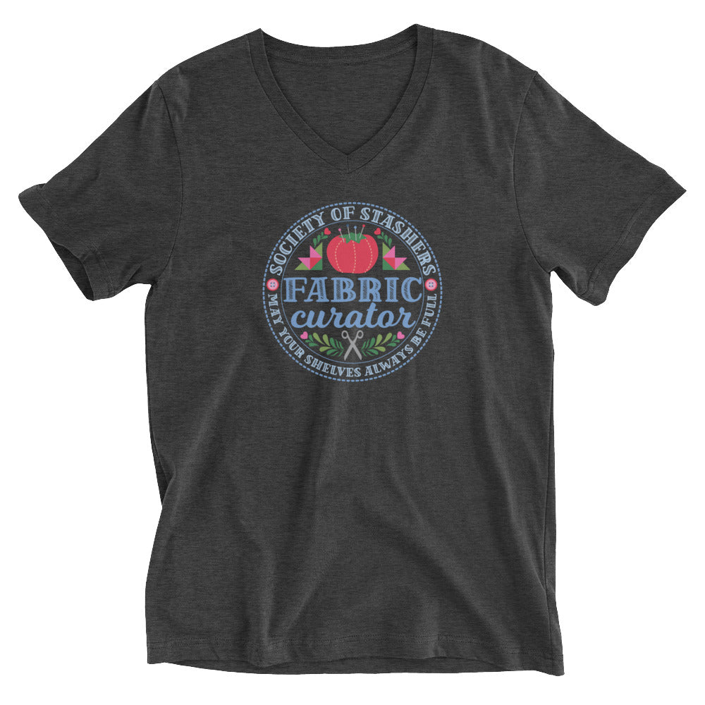 Fabric Curator Society of Stashers crest with a tomato pincushion on a unisex v-neck tee in dark grey heather, front view – Kate Spain design for Pat Sloan